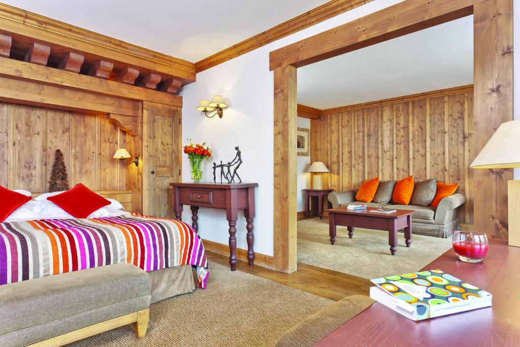 a bedroom with a bed and a living room at Hôtel Les Barmes De l'Ours in Val-d'Isère