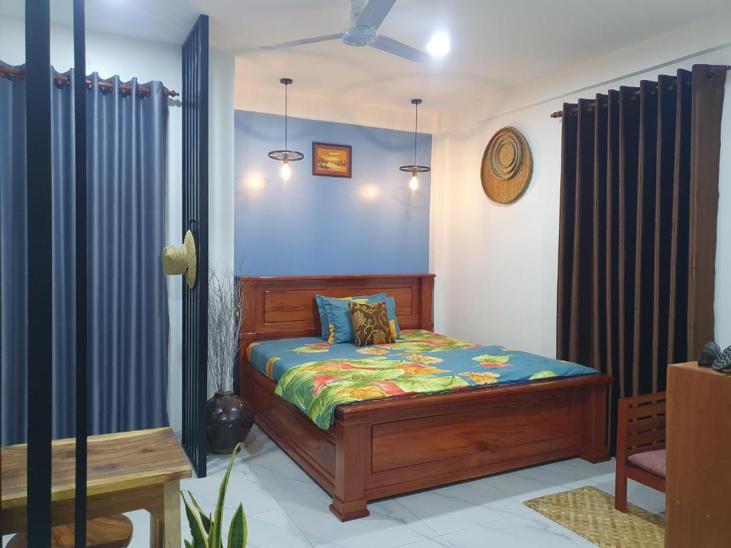 een slaapkamer met een bed met blauwe muren bij Kitya Homestay in Phumĭ Ta Phŭl