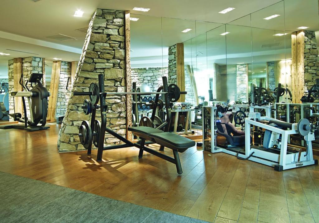 a gym with several tread machines and a stone wall at Hôtel Les Barmes De l'Ours in Val-d'Isère