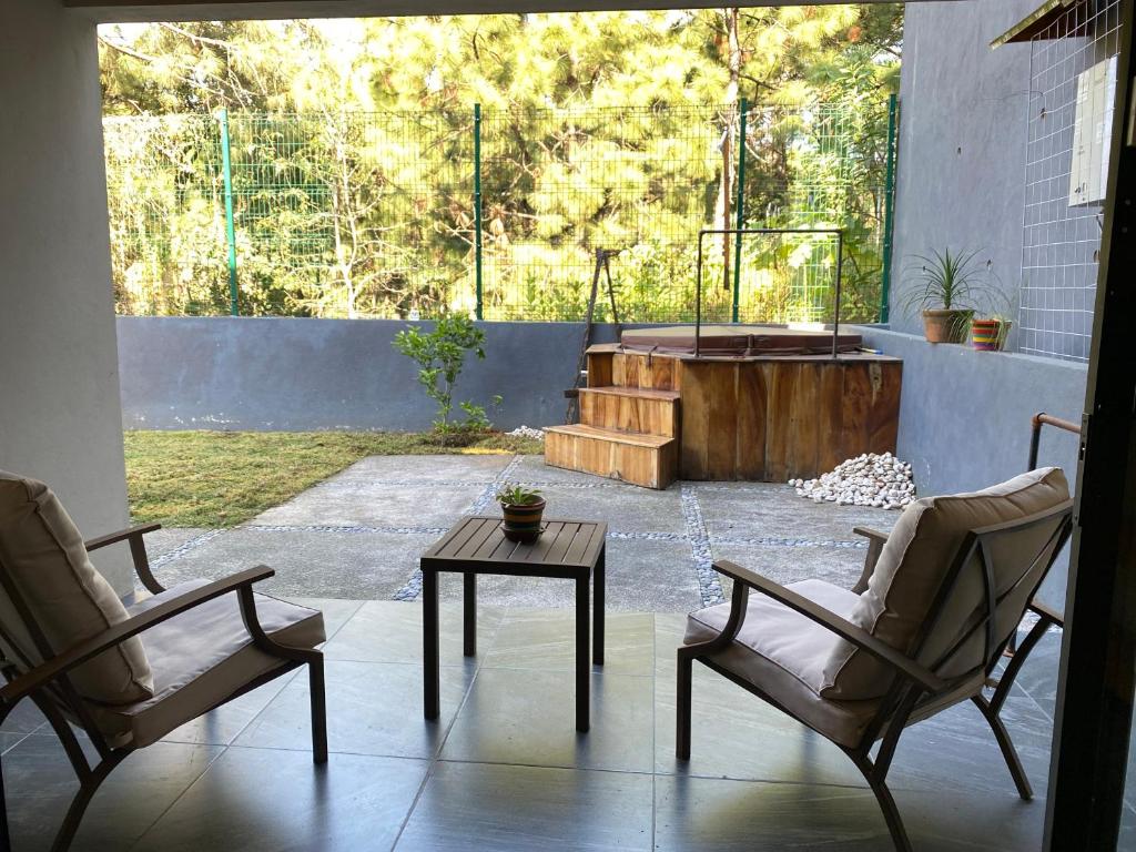 a patio with two chairs and a table and a tub at Casa para 6 en Valle, Naturaleza, jacuzzi y descanso in Valle de Bravo