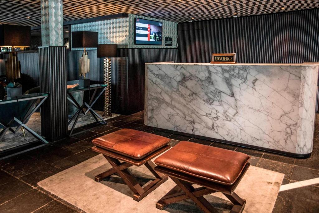 a lobby with two stools and a marble counter at Apollo Hotel Amsterdam, a Tribute Portfolio Hotel in Amsterdam
