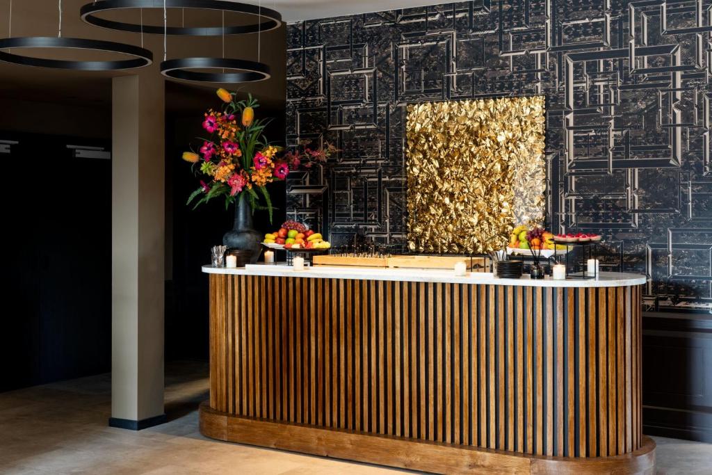 a lobby with a reception counter with flowers on it at Apollo Hotel Amsterdam, a Tribute Portfolio Hotel in Amsterdam