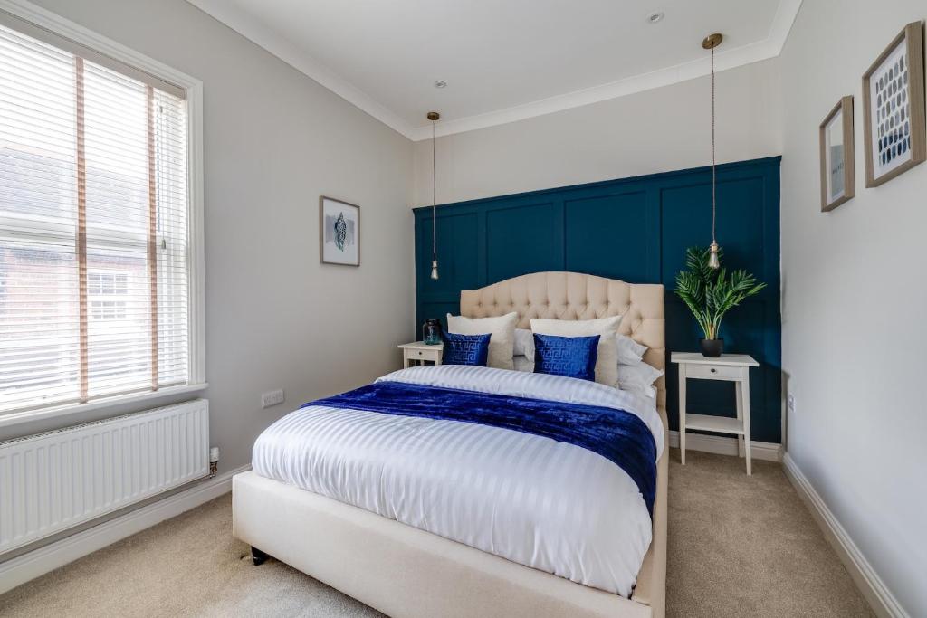 a bedroom with a large bed with a blue headboard at Royal Chester Retreat - Rose Platinum Properties in Chester