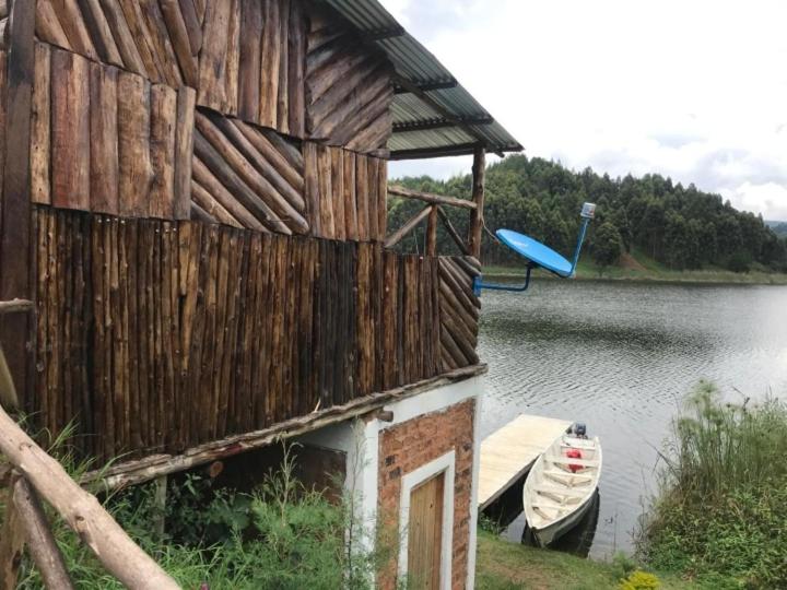 un edificio de madera con un barco en un lago en Weaver Bird Hostel, en Rubanda