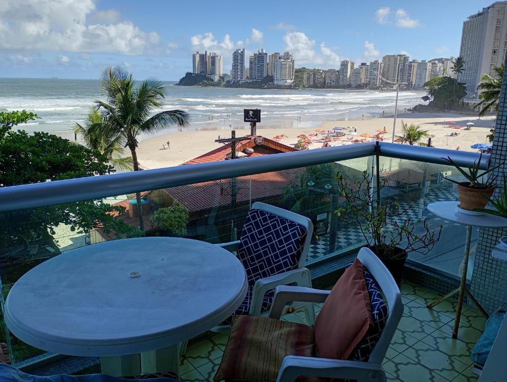 a balcony with a table and chairs and a beach at PITANGUEIRAS LINDO FRENTE AO MAR 4 QUARTOs in Guarujá