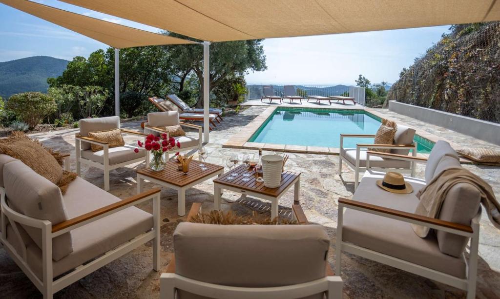 un patio avec des chaises et une piscine avec vue dans l'établissement Villa Mimosa, climatisée avec Piscine et Vue Mer pour 10 personnes à La Londe-Les-Maures, à La Londe-les-Maures