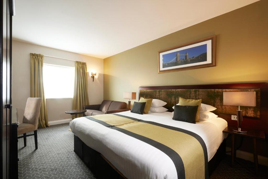 a hotel room with a large bed and a chair at Stamford Bridge Hotel London in London