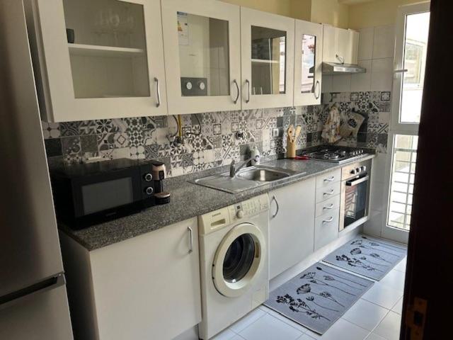 a kitchen with a sink and a washing machine at Caniço Easy Stay in Caniço