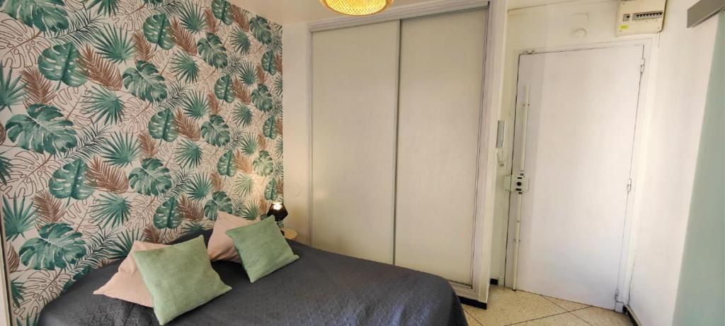 une chambre avec un lit avec un papier peint tropical dans l'établissement Cosy studio for 2, à Saint-Raphaël
