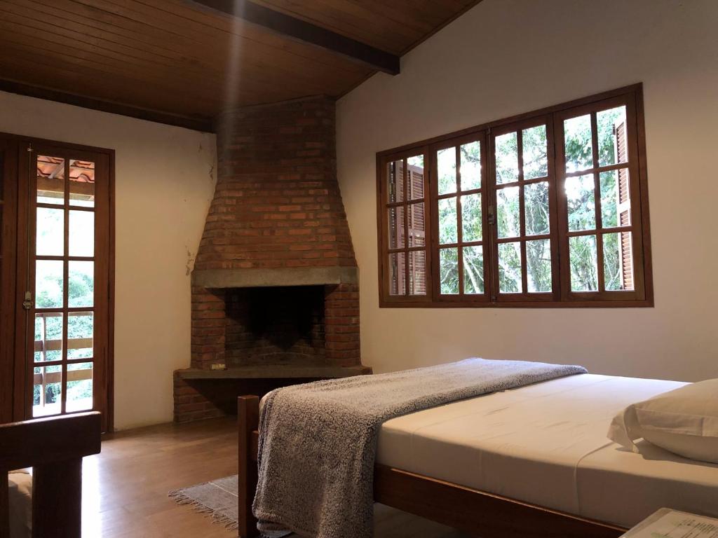 - une chambre avec un lit et une cheminée en briques dans l'établissement Pousada SerTão de Minas, à Conceição da Ibitipoca