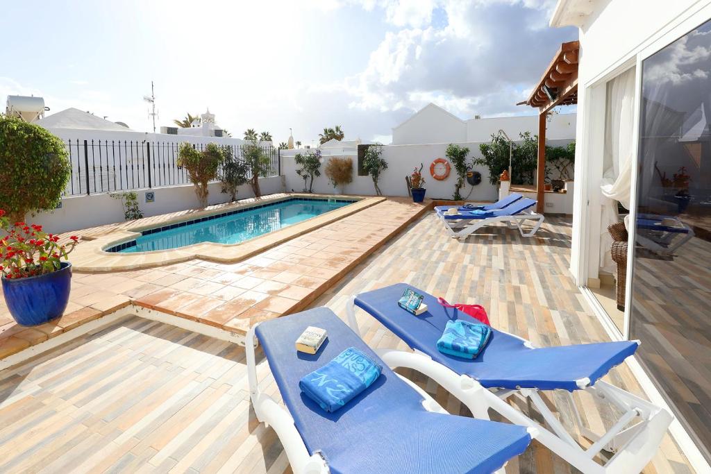 a swimming pool with two blue chairs and a swimming pool at Casa de Suėños in Puerto del Carmen