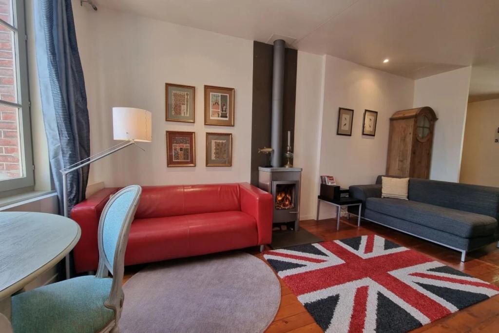 a living room with a red couch and a table at La Maison du Puits with wood-burning stove Honfleur center 5P in Honfleur