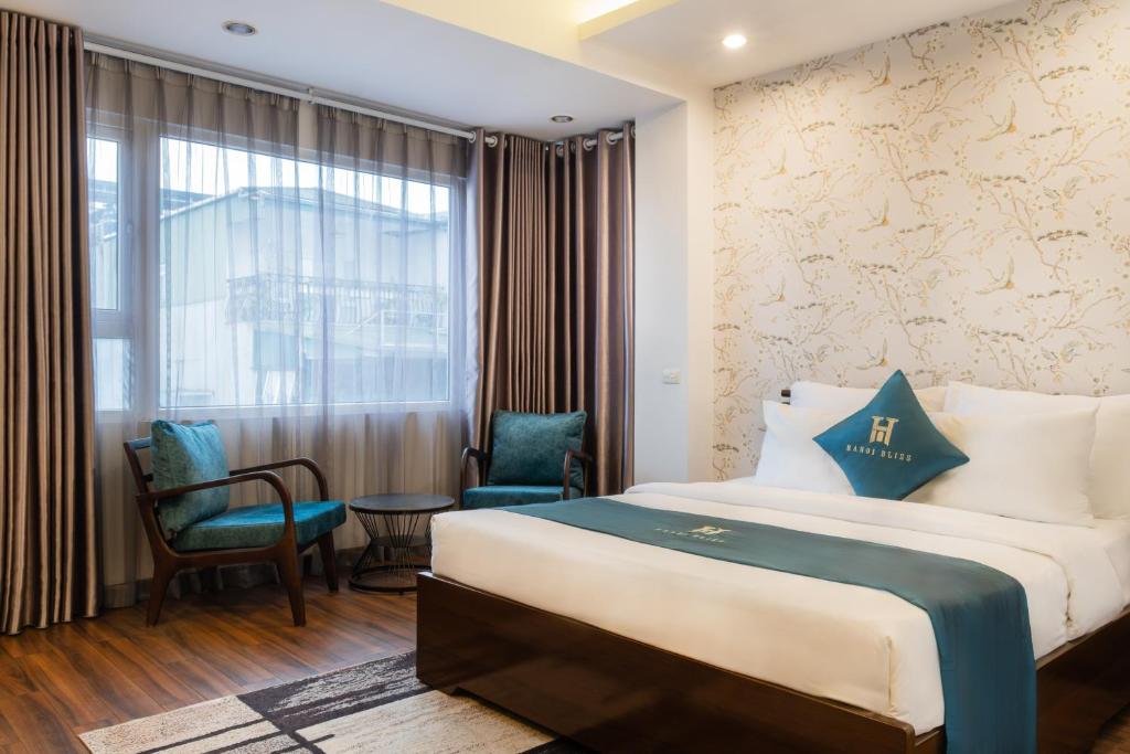 a hotel room with a bed and chairs and a window at Hanoi Bliss Mai Hac De in Hanoi
