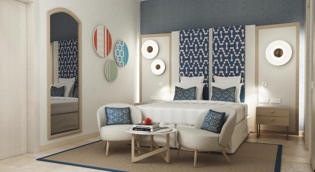a bedroom with a bed and a chair and a table at Almar Timi Ama Resort & Spa in Villasimius