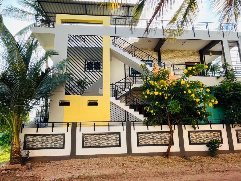 un edificio giallo e bianco con un albero di fronte di Happy Hampi Home a Hospet