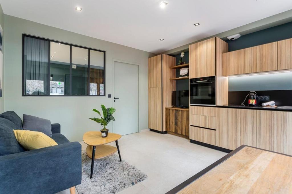 un salon avec un canapé bleu et une table dans l'établissement Hamac Suites - Suite du Parc 2, à Villeurbanne