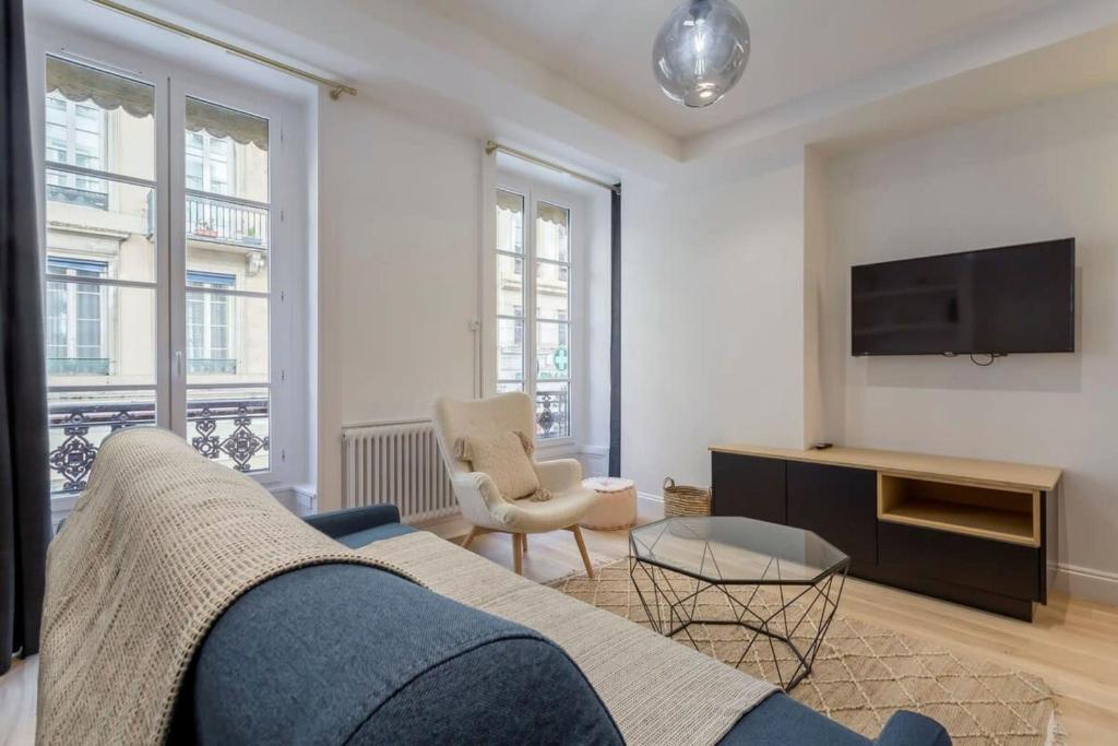 a living room with a blue couch and a tv at Superb apartment in the heart of the peninsula - Air-conditioned in Lyon
