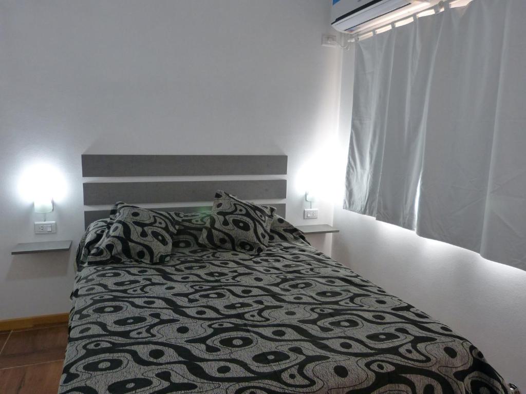 1 cama en un dormitorio con 2 luces encendidas en Santa Isabel Departamentos, en Valle María