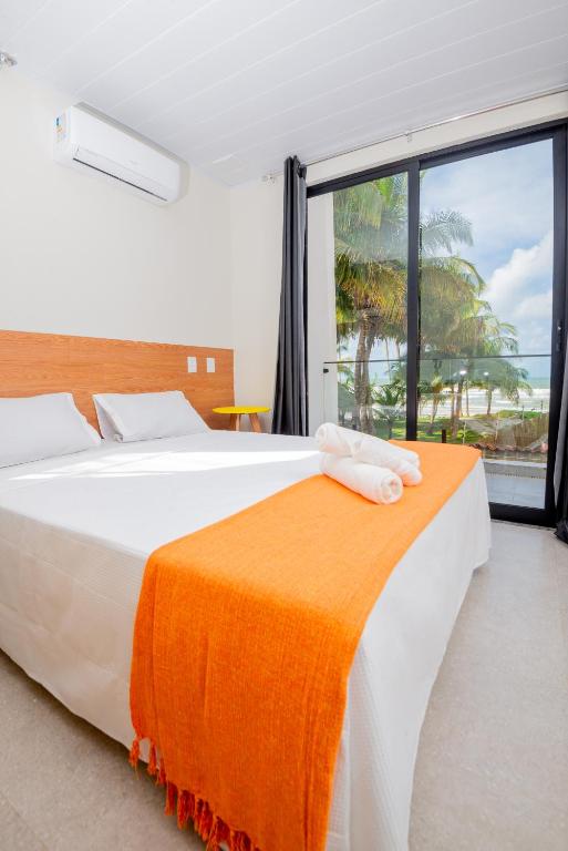 a bedroom with a large bed with an orange blanket at Casa Pé na Areia a 10m da Praia! Imperdível! in Olivença