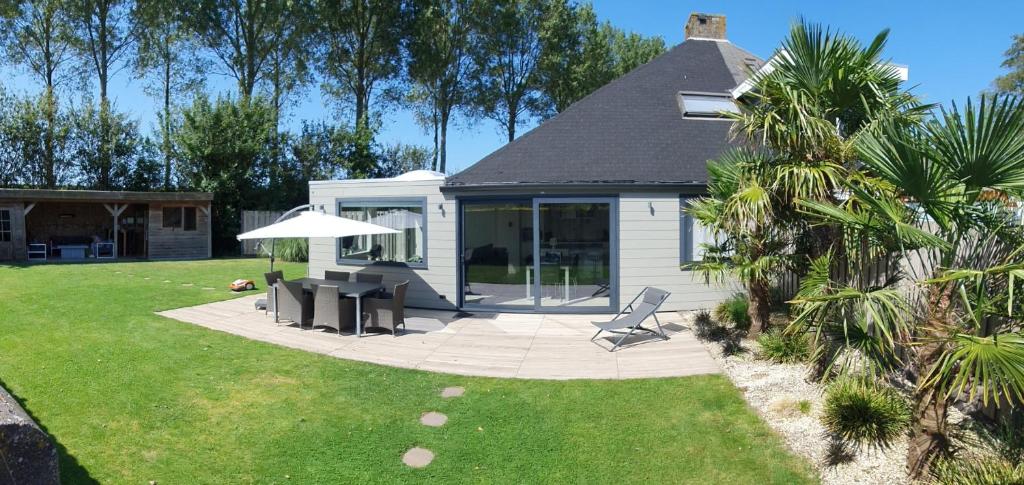 a house with a patio with a table and an umbrella at Holiday cottage with sauna in Zeeland in Stavenisse
