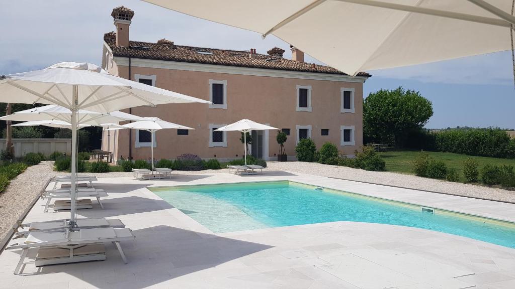 Una piscina con sombrillas y sillas y una casa. en Villa Montefiore Country Resort, en Borghetto