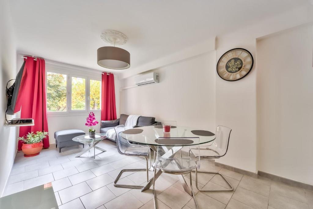 - un salon avec une table, des chaises et une horloge dans l'établissement Modern 2BR Flat - Haut de Nice, à Nice