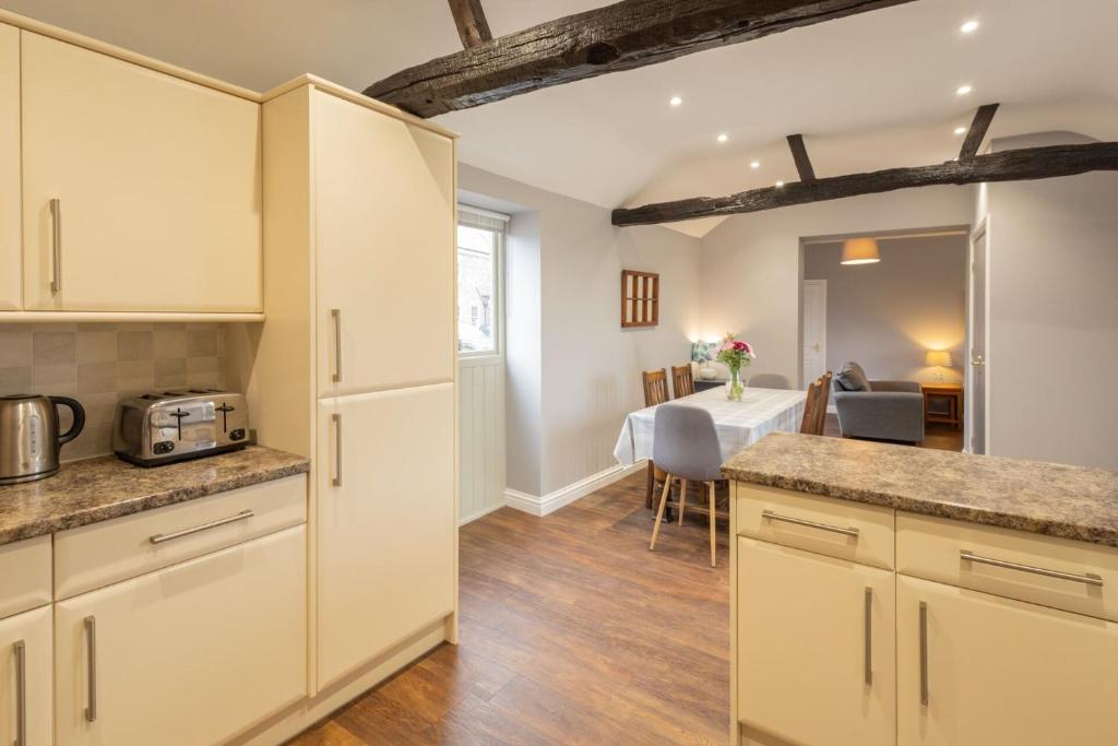 a kitchen with white cabinets and a dining room at Host & Stay - Croft Cottage in Pickering