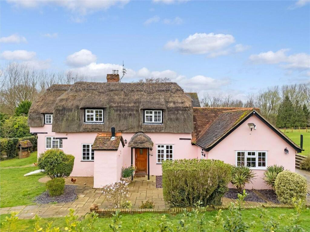 a large pink house with a thatched roof at Blackbrook Farmhouse in Colchester