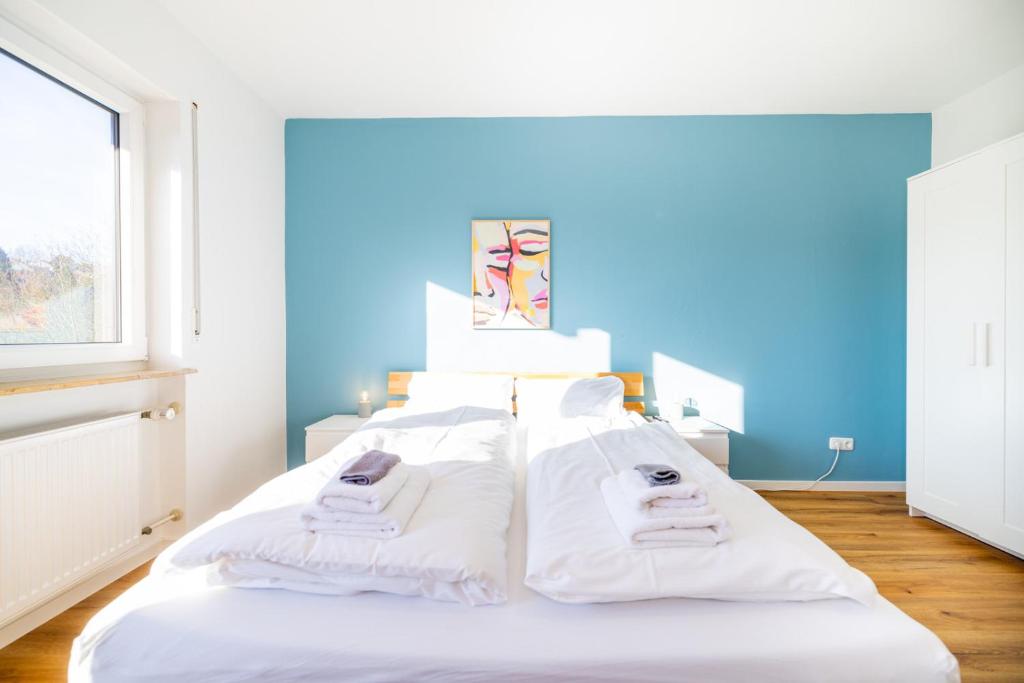 a bedroom with a bed with white sheets and a blue wall at Gemütliche, moderne Ferienwohnung in Stadtnähe in Würzburg