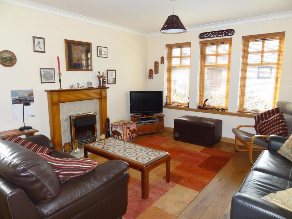a living room with leather furniture and a fireplace at Dullatur in Newtonmore