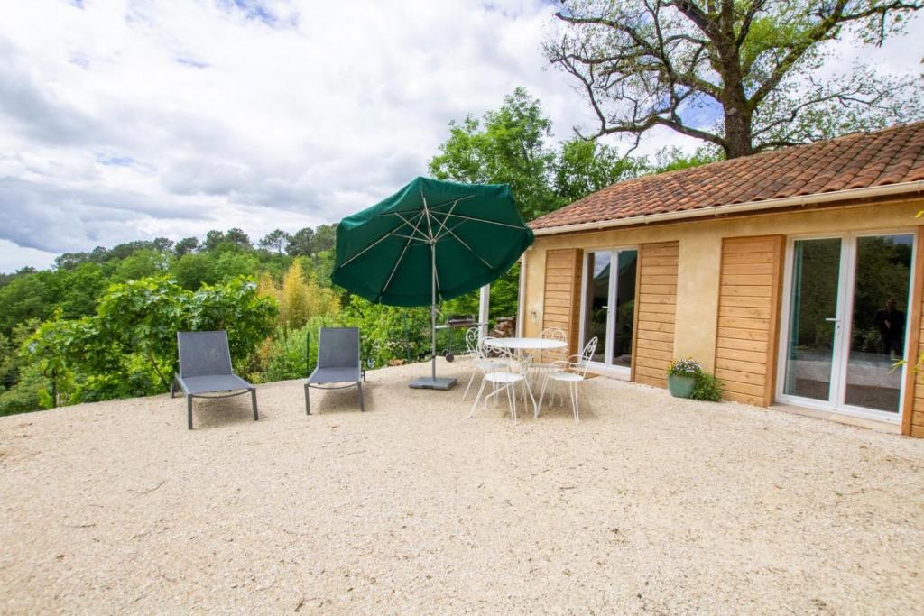 un patio avec une table, des chaises et un parasol dans l'établissement Chez flo et guillaume, à Saint-André-dʼAllas