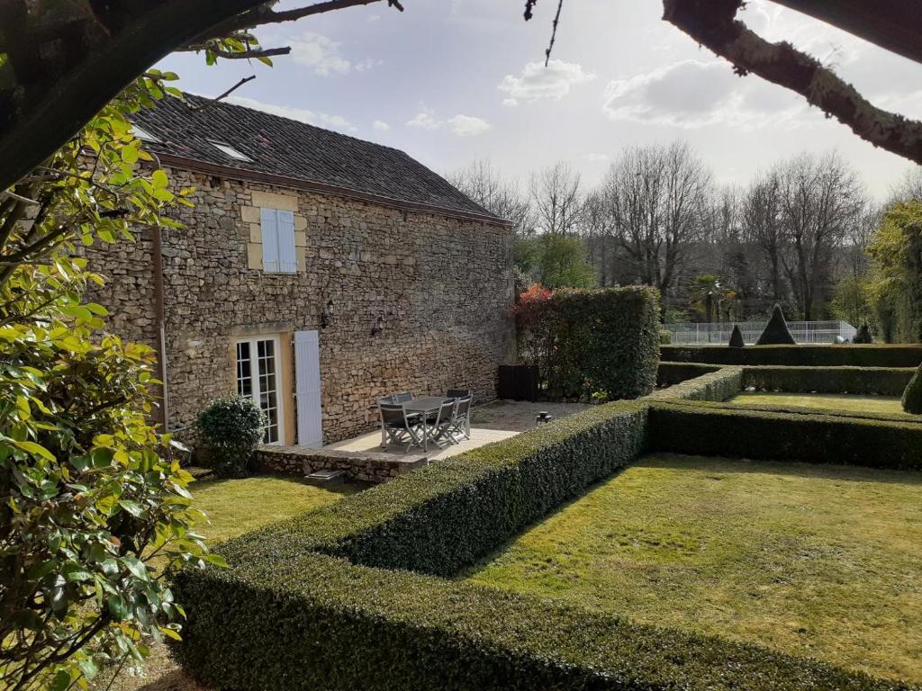 une maison en pierre avec un banc dans un jardin dans l'établissement Domaine de pommarede, à Carsac-Aillac