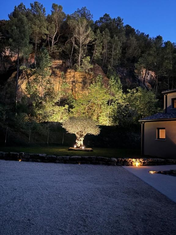 un arbre au milieu d'une cour avec un bâtiment dans l'établissement Villa Lynaë, à Saint-Restitut