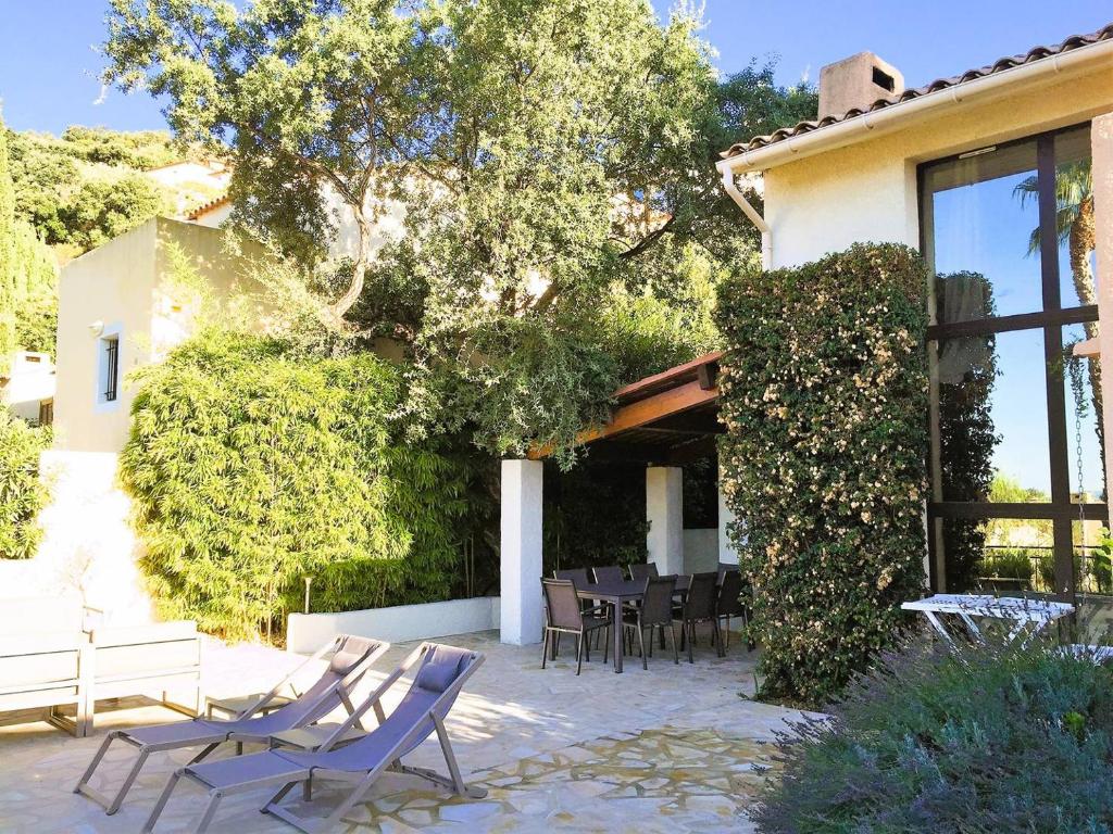 un patio avec des chaises et une table devant un bâtiment dans l'établissement Les Medes pour 7 personnes sur le Domaine de Valcros, à La Londe-Les-Maures, à La Londe-les-Maures