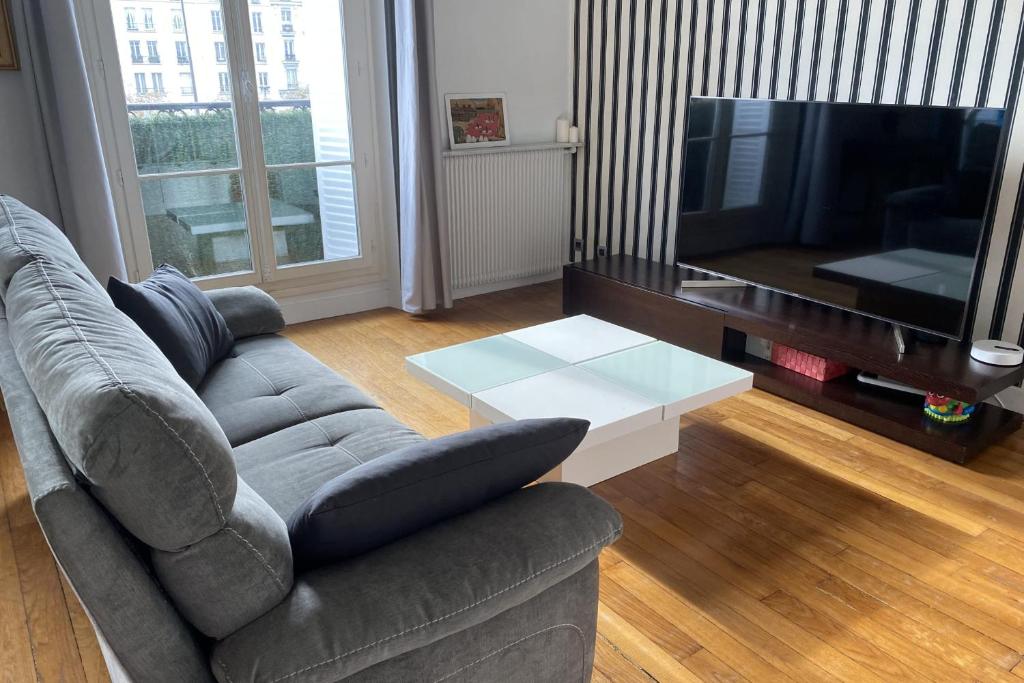 un salon avec un canapé et une télévision à écran plat dans l'établissement Bright Haussmann apartment near Nation, à Paris