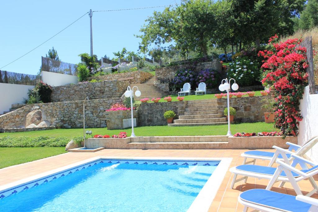 una piscina en un patio con 2 sillas y flores en Apartamentos Maritimo Suites-Solo Adultos, en O Grove