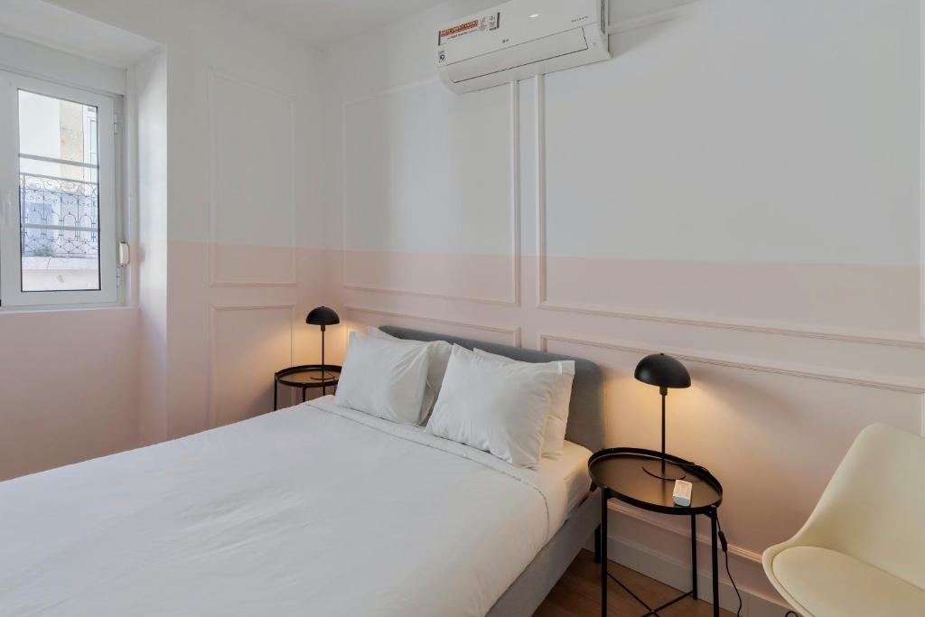 a bedroom with a white bed with two lamps and a chair at City Life in Setubal