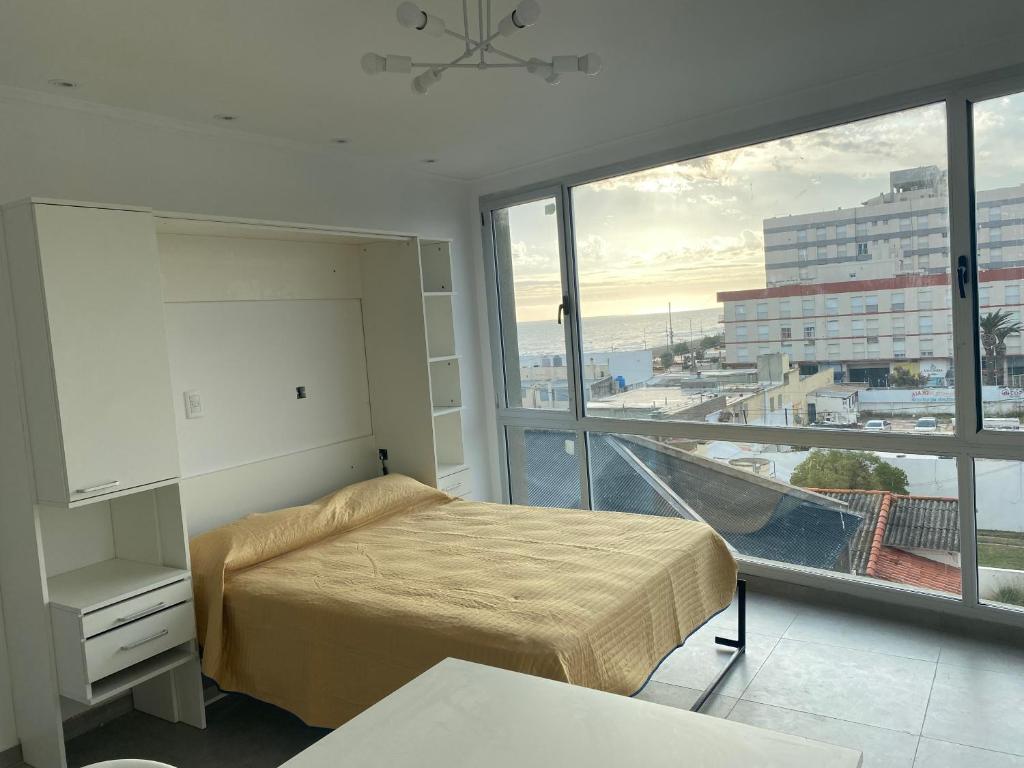 Un dormitorio con una cama y una ventana grande. en J-M-L DEPARTAMENTO 5a, en Monte Hermoso