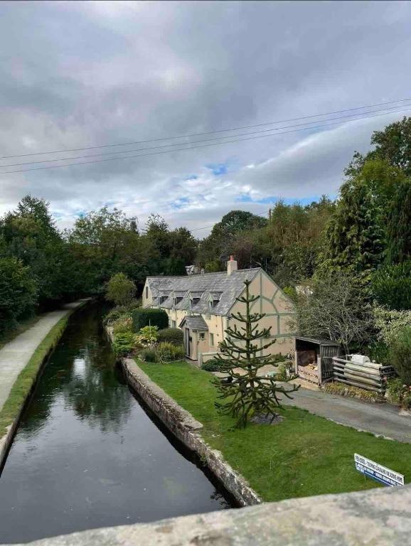 a house with a river in front of it at Penddol Cottage & Boathouse in Llangollen