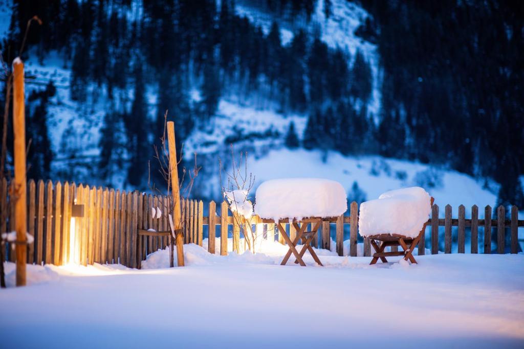 Dos sillas cubiertas de nieve delante de una valla en Ferienlodge Alpenkönigin - Apartments Stubaital, en Neustift im Stubaital