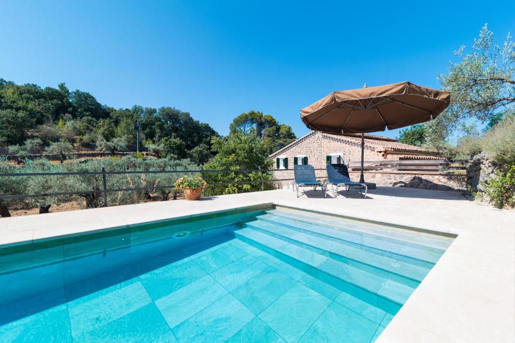 ein Swimmingpool mit Sonnenschirm und ein Haus in der Unterkunft Es Coll d'en Pastor in Fornalutx