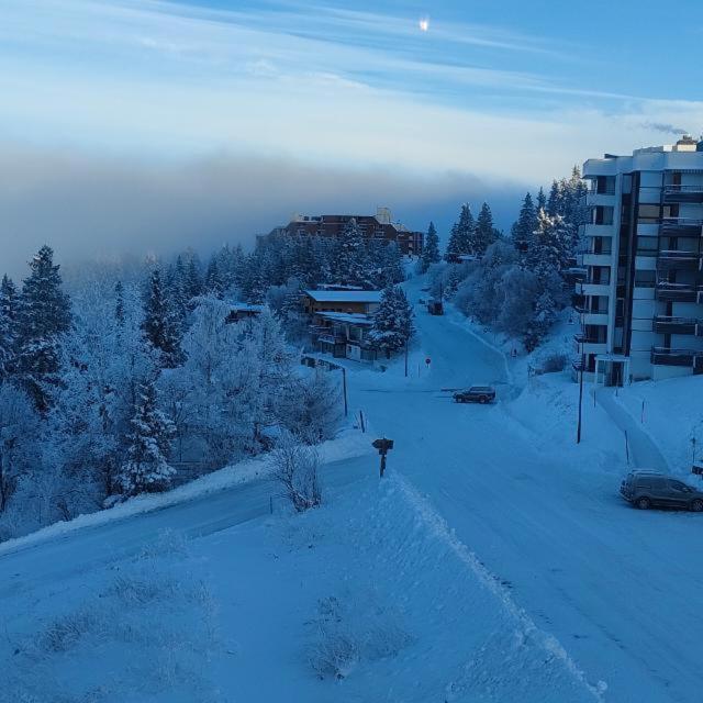 une rue enneigée avec un bâtiment en arrière-plan dans l'établissement Chamrousse 1750 Studio 4 personnes 29m2, à Chamrousse