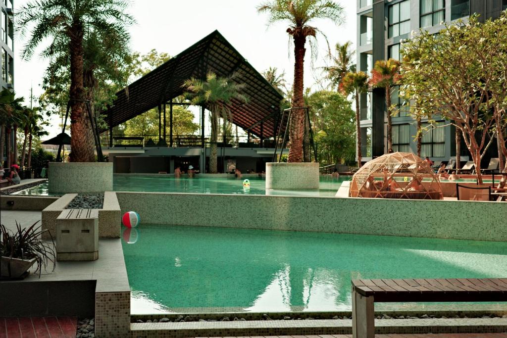 einen Pool in einem Gebäude mit Palmen in der Unterkunft City Gate Kamala B216 by Phuket Sabay Rent in Phuket