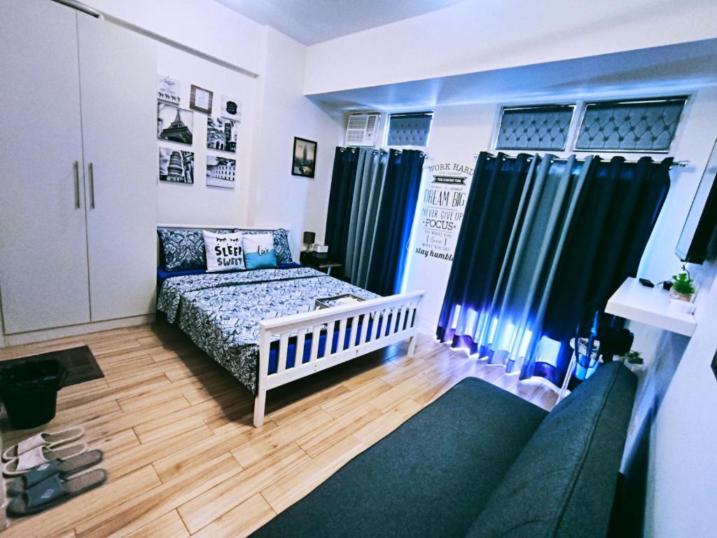 Cabilang BaybayにあるTessa's Place Staycation 4Fkの青いカーテンとベビーベッド付きの小さなベッドルーム1室