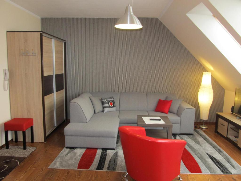a living room with a couch and red chairs at Apartament Studio in Giżycko