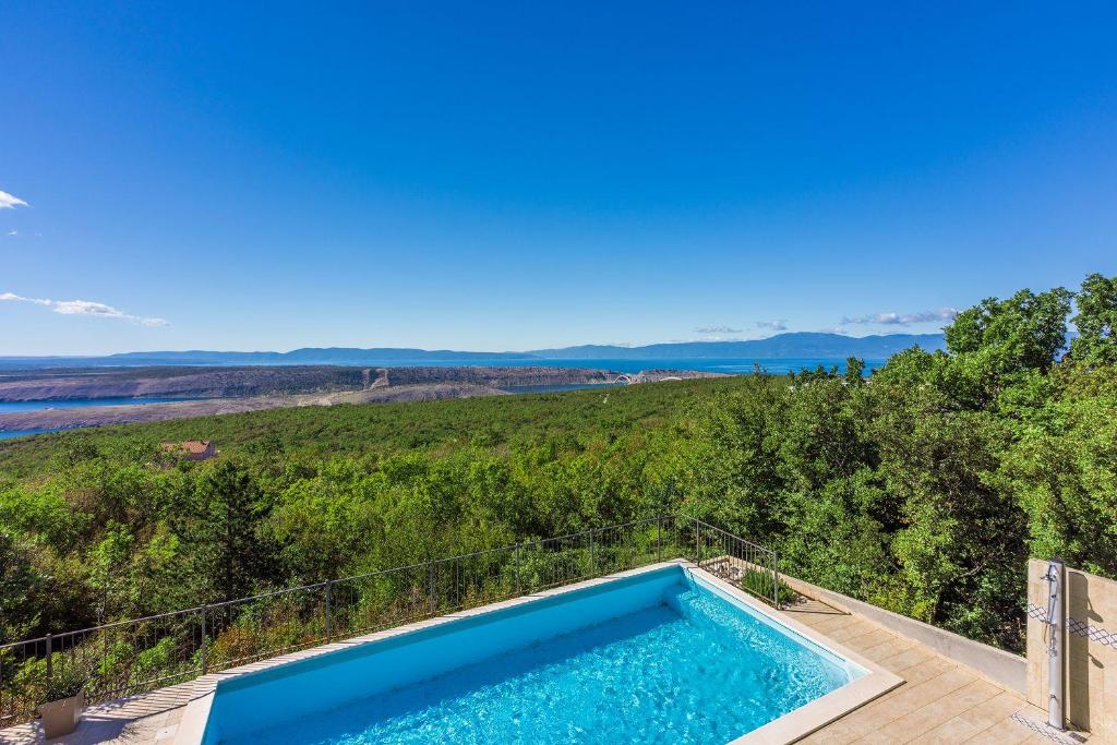 an outdoor swimming pool with a view of a hill at Faszinierende Villa mit traumhaften Meerblick zur Insel Krk mit Privatpool, Tischtennis, Billard, Grill in Šmrika