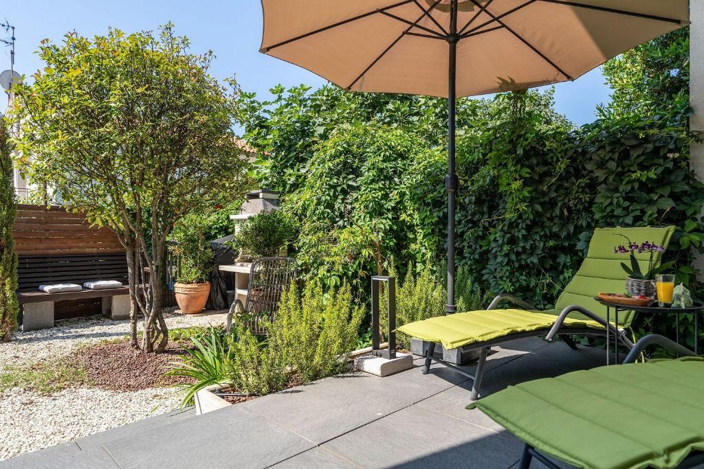 un patio con ombrellone, tavolo e sedie di Exquisites Ferienhaus mit privatem Garten, Liegen, Kinderstuhl, Waschmaschine - nur 700 Meter zum Strand a Poreč (Parenzo)