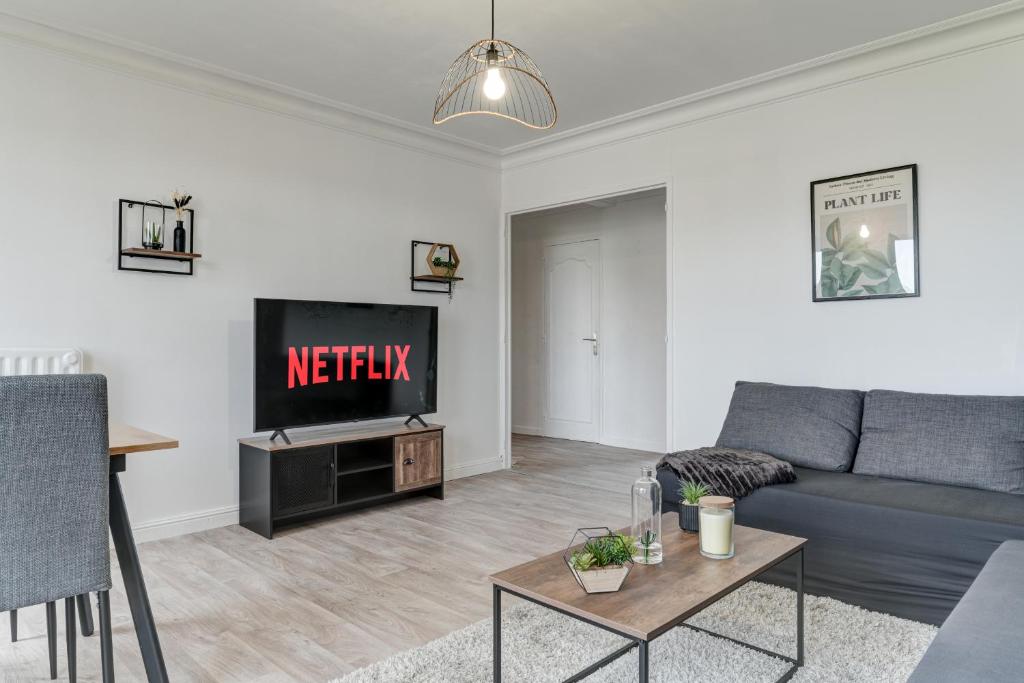 un salon avec un canapé et une télévision dans l'établissement Le Cosy, à Saint-Priest