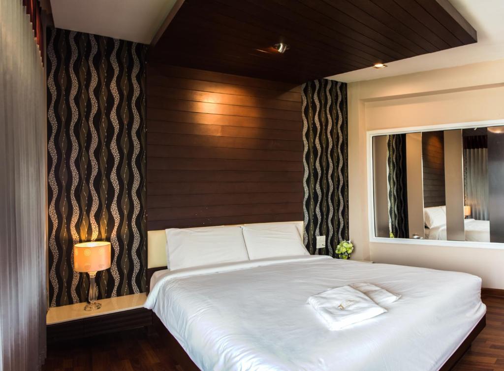 1 dormitorio con 1 cama blanca grande y espejo en The Ring Hotel, en Hat Yai