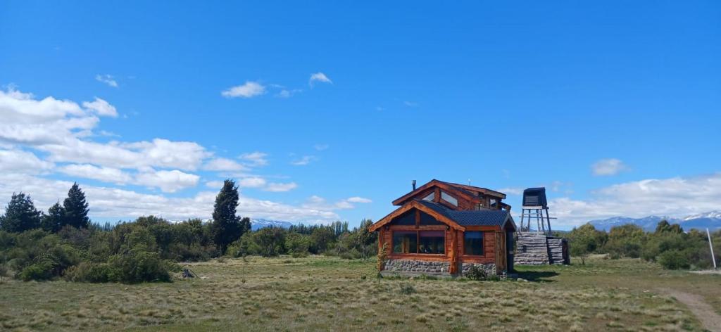 a small wooden house in a field with a chair at Los Trevelinos in Trevelin
